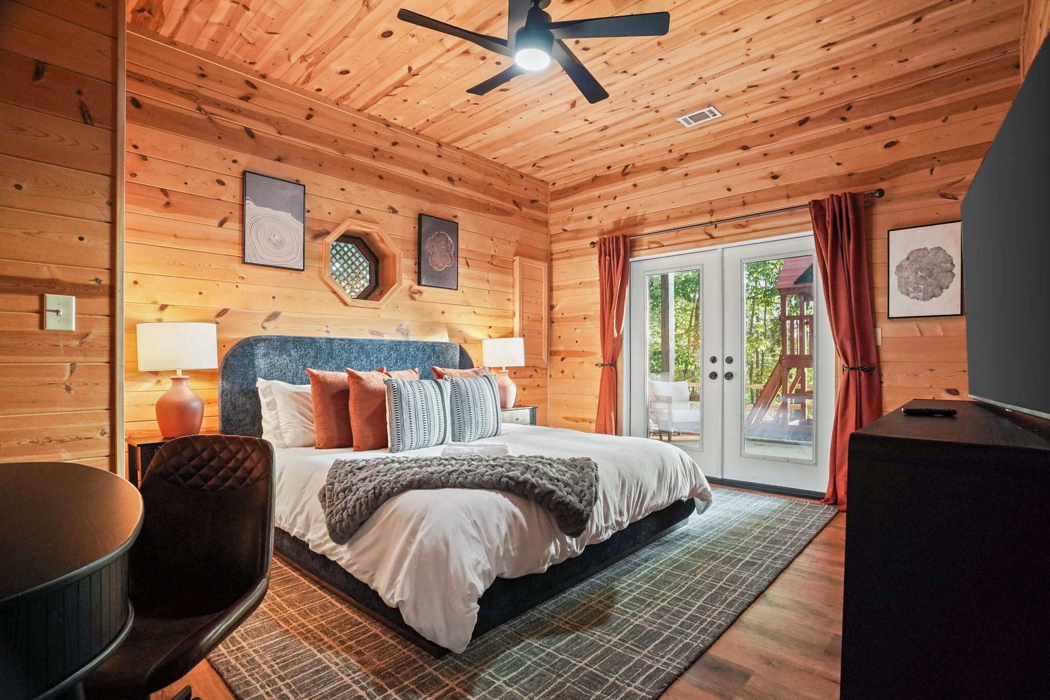 A wooden cabin bedroom with a bed, a desk, and a chair.