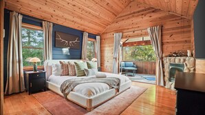 Ein geräumiges Schlafzimmer mit einem großen Bett, einem Nachttisch, einer Kommode und einem Kamin aus Stein.