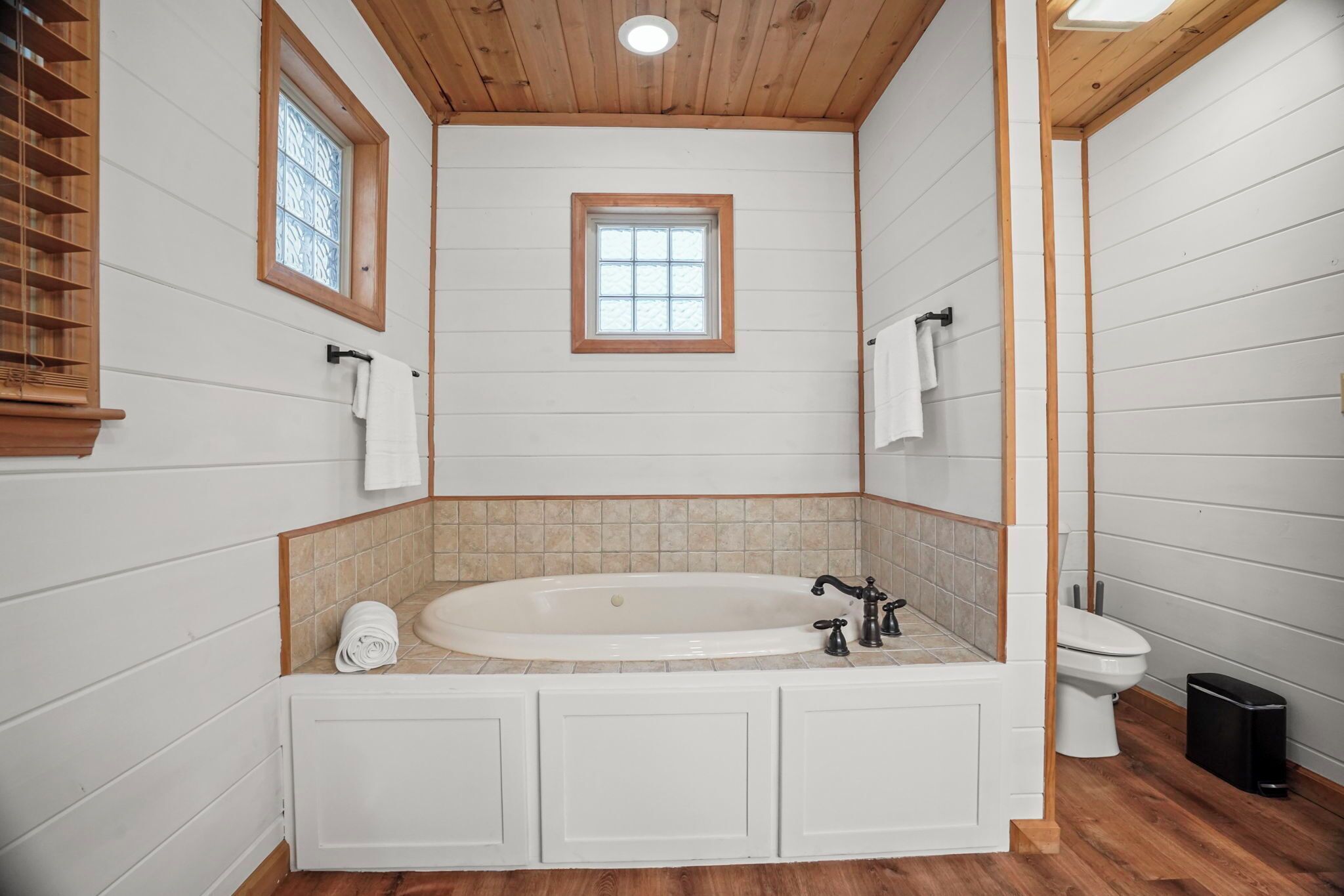 Un baño con una bañera independiente, un inodoro y una ventana.