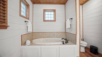 Un baño con una bañera independiente, un inodoro y una ventana.