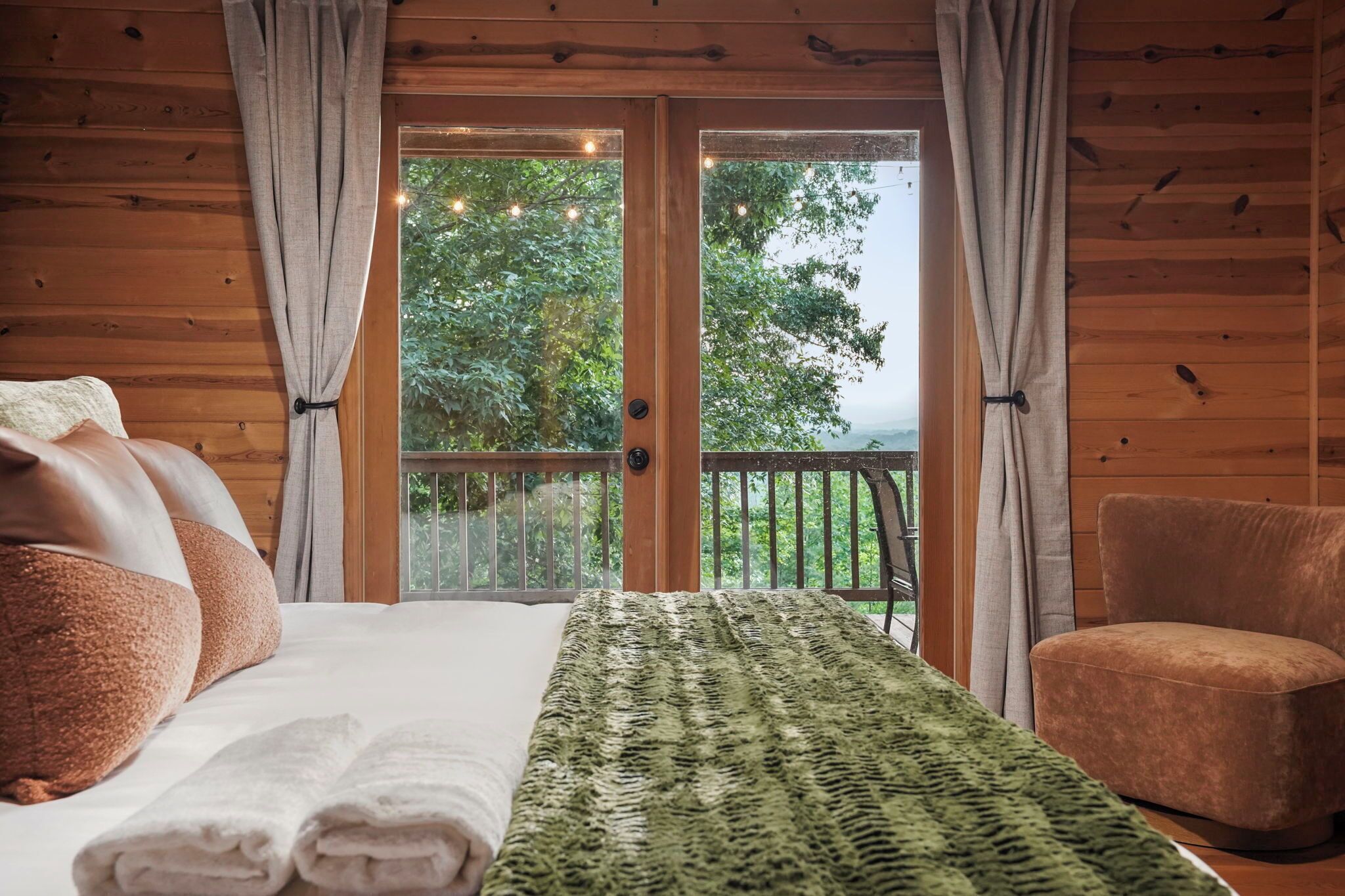 Une chambre dans un chalet en bois, avec un lit, une chaise et un balcon donnant sur la forêt.
