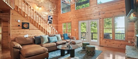 A spacious living room with a wooden staircase, a leather sofa, a round coffee table, and a fireplace.