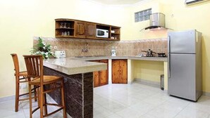 Una cocina con isla integrada, armarios de madera, microondas, estufa y refrigerador.