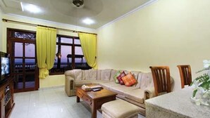 Una sala de estar con sofá, una mesa de centro, un mueble para televisor y una mesa de comedor con sillas.