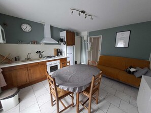 A compact kitchen with a dining table and chairs, a sofa, and a clock on the wall. - Apartment Veronica - your cocoon with terrace in the center of La Bourboule (La Bourboule)