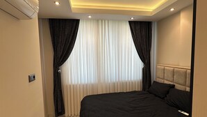 Un dormitorio moderno con una cama grande, una lámpara en el techo y un ventanal con cortinas.