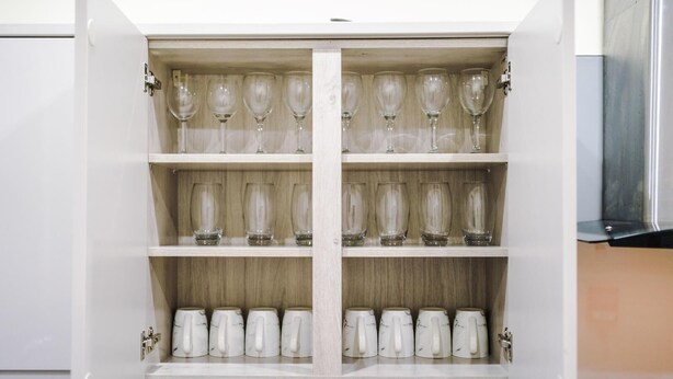 Un armario de cocina con copas de vino y tazas de café.
