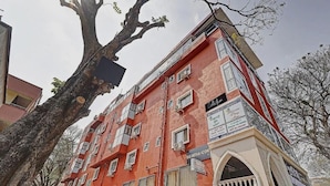 Un edificio a più piani con facciata rossa, diversi balconi e un cartello che indica un servizio di raccolta.