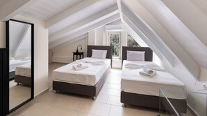 A bedroom with two beds, a large mirror, and a view of trees through a window. - Carmen Sea View Maisonette (Lefkada)