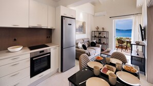 A modern kitchen with a built-in oven, a stainless steel refrigerator, and a dining area with a table set for a meal. - Carmen Sea View Maisonette (Lefkada)