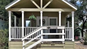 A single-story building with a porch, a staircase, and a small front yard. - NEW! Resort and Cozy Cottage (Austin)