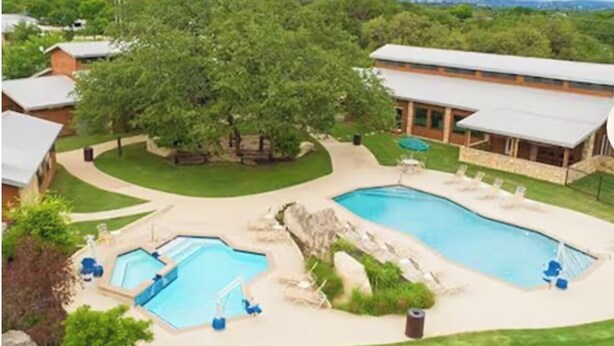 A residential area with two swimming pools, a large tree, and a house with a covered patio. - NEW! Resort and Cozy Cottage (Austin)