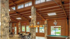A pool table in a room with stone pillars, wooden beams, and a view of the outdoors. - NEW! Resort and Cozy Cottage (Austin)