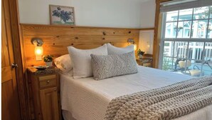A bedroom with a wooden headboard, a bed with white bedding, two bedside tables with lamps, and a window with a view of buildings. - NEW! Resort and Cozy Cottage (Austin)