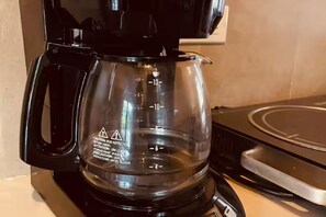 Una moka nera con caraffa in vetro trasparente su un piano di lavoro in cucina.