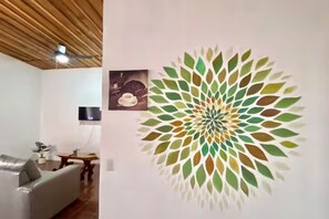 Een woonkamer met houten plafond, een bank, een tafel en een kunstwerk aan de muur.