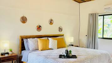 Een slaapkamer met een houten bedframe, een wit beddegoed met structuur en een nachtkastje met een lamp en een kleine plant.