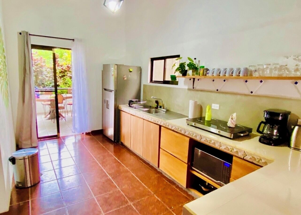 A kitchen with a refrigerator, microwave, sink, and a coffee maker.