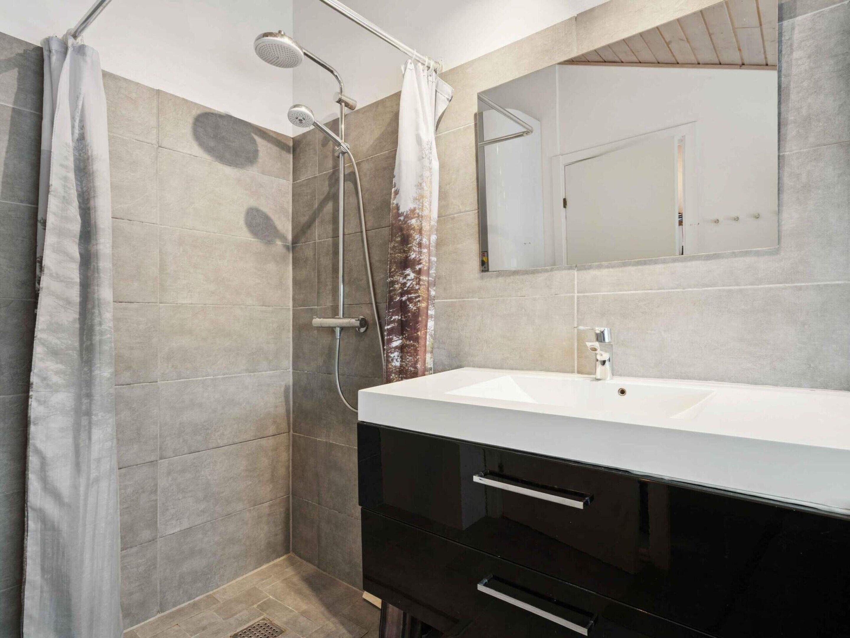 Un baño moderno con ducha, lavabo y espejo.