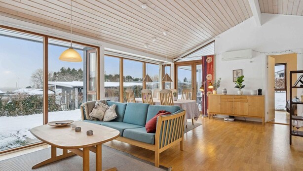 A spacious room with a wooden ceiling, large windows, a sofa, a dining table, and a cabinet. - 4 Star Holiday Home in Ronde (Ronde)