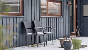 A building with two windows and a door, two wicker chairs outside, and two potted plants. - 4 Star Holiday Home in Ronde (Ronde)