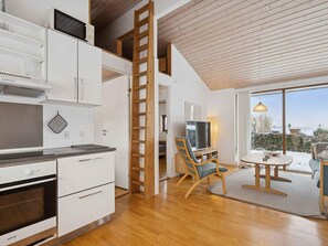 A modern kitchen with white cabinets, a built-in oven, and a wooden ladder. - 4 Star Holiday Home in Ronde (Ronde)
