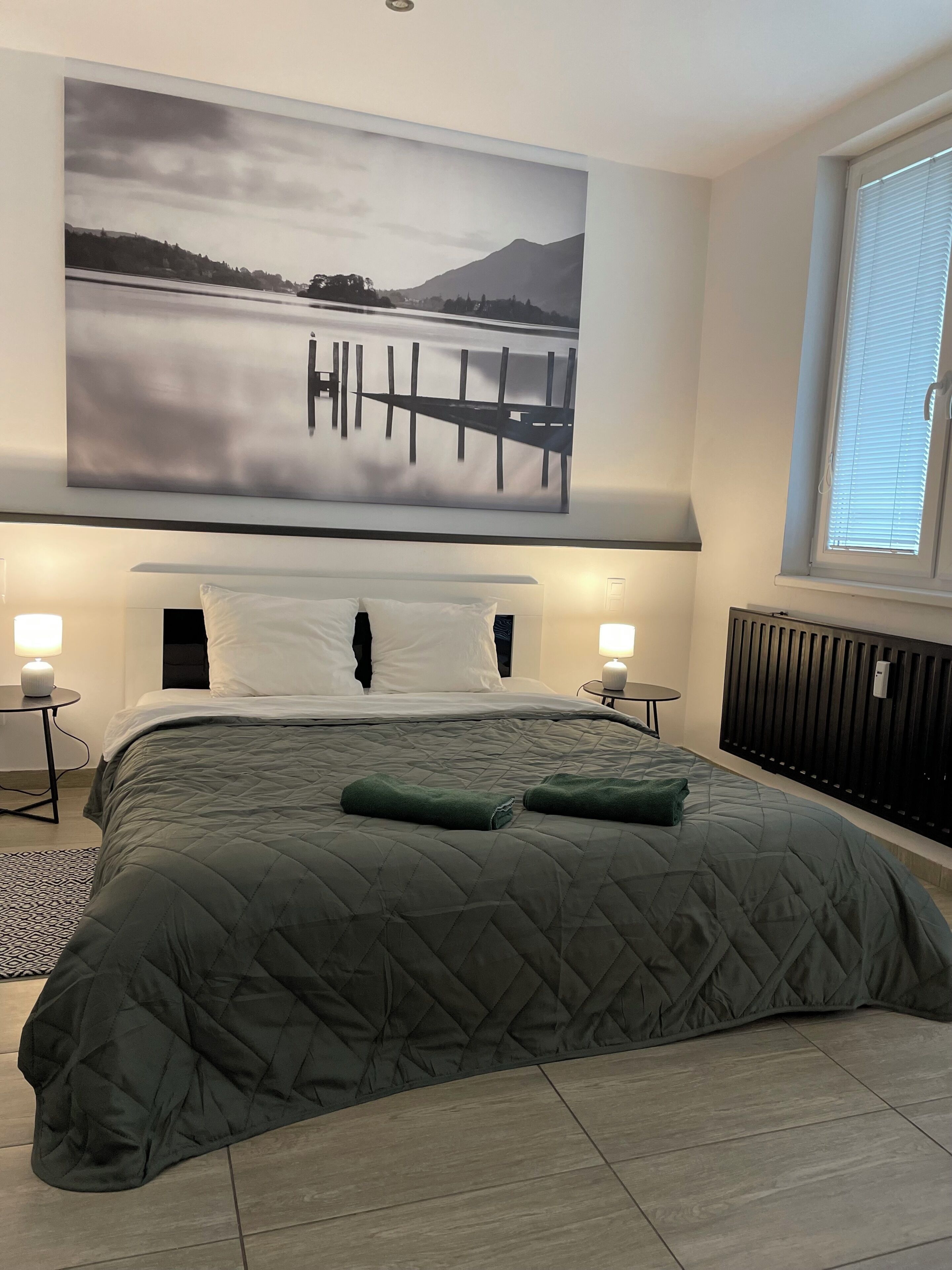 Ein Schlafzimmer mit einem großen Bett, Seeblick und einem Berg im Hintergrund.