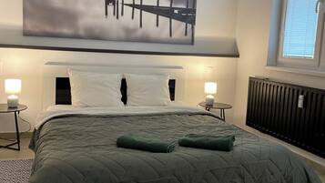 Ein Schlafzimmer mit einem großen Bett, Seeblick und einem Berg im Hintergrund.