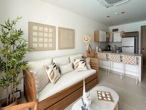 A modern living room with a sofa, a coffee table, and a kitchen area with a bar. - Stunning Lagoon View Condo w/ Beach, Pool & Jacuzzi (Cartagena)