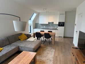 A modern apartment with a living room, dining area, kitchen, and a large window. - Modern Apartment Hasselt 2p (Hasselt)