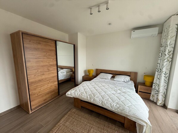 A bedroom with a bed, a wardrobe, a mirror, a bedside table, and an air conditioning unit. - Modern Apartment Hasselt 2p (Hasselt)