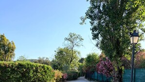 A park with a gravel path, benches, and trees. - La  parenthèse de Villepey (Fréjus)