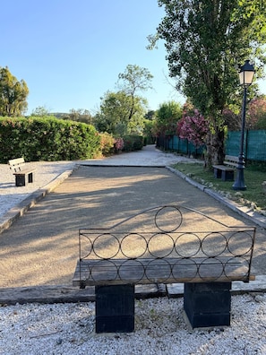 Um parque com trilha de cascalho, bancos e árvores.