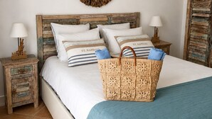 A bed with a wooden headboard, two bedside tables, a wall-mounted decorative piece, and a woven basket on the bed. - La  parenthèse de Villepey (Fréjus)