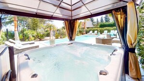 A hot tub with a view of a pool and lounge chairs. - La  parenthèse de Villepey (Fréjus)