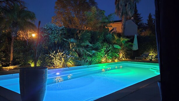 A swimming pool with a view of a garden and a building in the background. - La  parenthèse de Villepey (Fréjus)