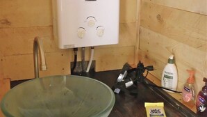 A bathroom with a white heater, a glass basin, and toiletries on the counter.