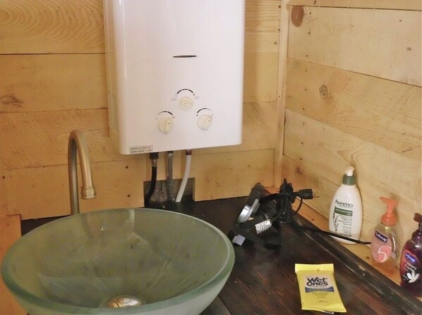 A bathroom with a white heater, a glass basin, and toiletries on the counter.