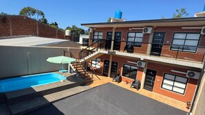 A two-story building with a swimming pool, outdoor seating, and a staircase leading to the upper floor. - Moonlight Iguazu Apart (Puerto Iguazú)