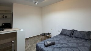 A modern bedroom with a bed, a desk, and a ceiling light fixture. - Moonlight Iguazu Apart (Puerto Iguazú)