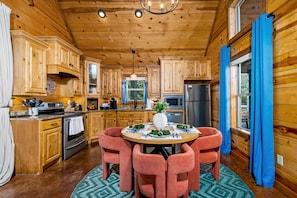 A wooden cabin interior with a kitchen, dining area, and large windows. - Firepit, Grill & Hot Tub - Private Spa Cabin for Two (Broken Bow)