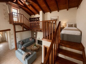Ein Loft-Zimmer mit einer Holztreppe, einer Couch, einem Bett und einem Kamin.
