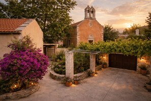 Ein Innenhof mit einer Kirche, Topfpflanzen und einer Pergola.
