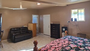 A room with a bed, a couch, a wardrobe, a desk, and a window.