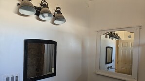 A bathroom with a sink, a mirror, and a wall-mounted light fixture.