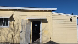 A building with a garage door, a door with a metal gate, and a window.