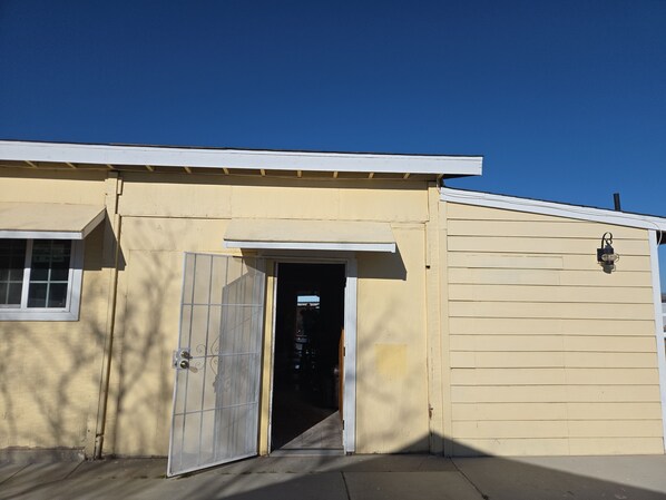 A building with a garage door, a door with a metal gate, and a window.