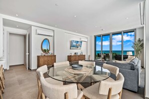Een moderne woonkamer met een glazen tafel, banken en uitzicht op de oceaan.
