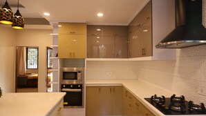 A modern kitchen with built-in appliances, a stove, and a window with curtains.