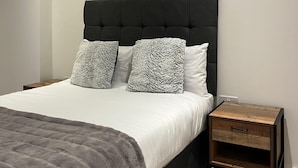 Ein modernes Schlafzimmer mit einem großen Bett, zwei Nachttischen und einem Kopfteil.